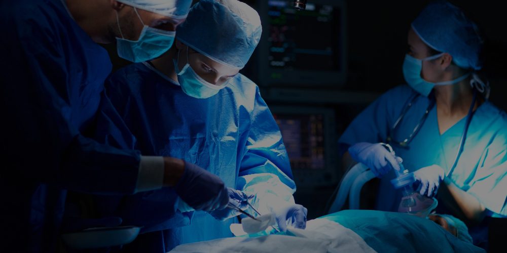 a imagem mostra três médicos realizando uma cirurgia em um paciente